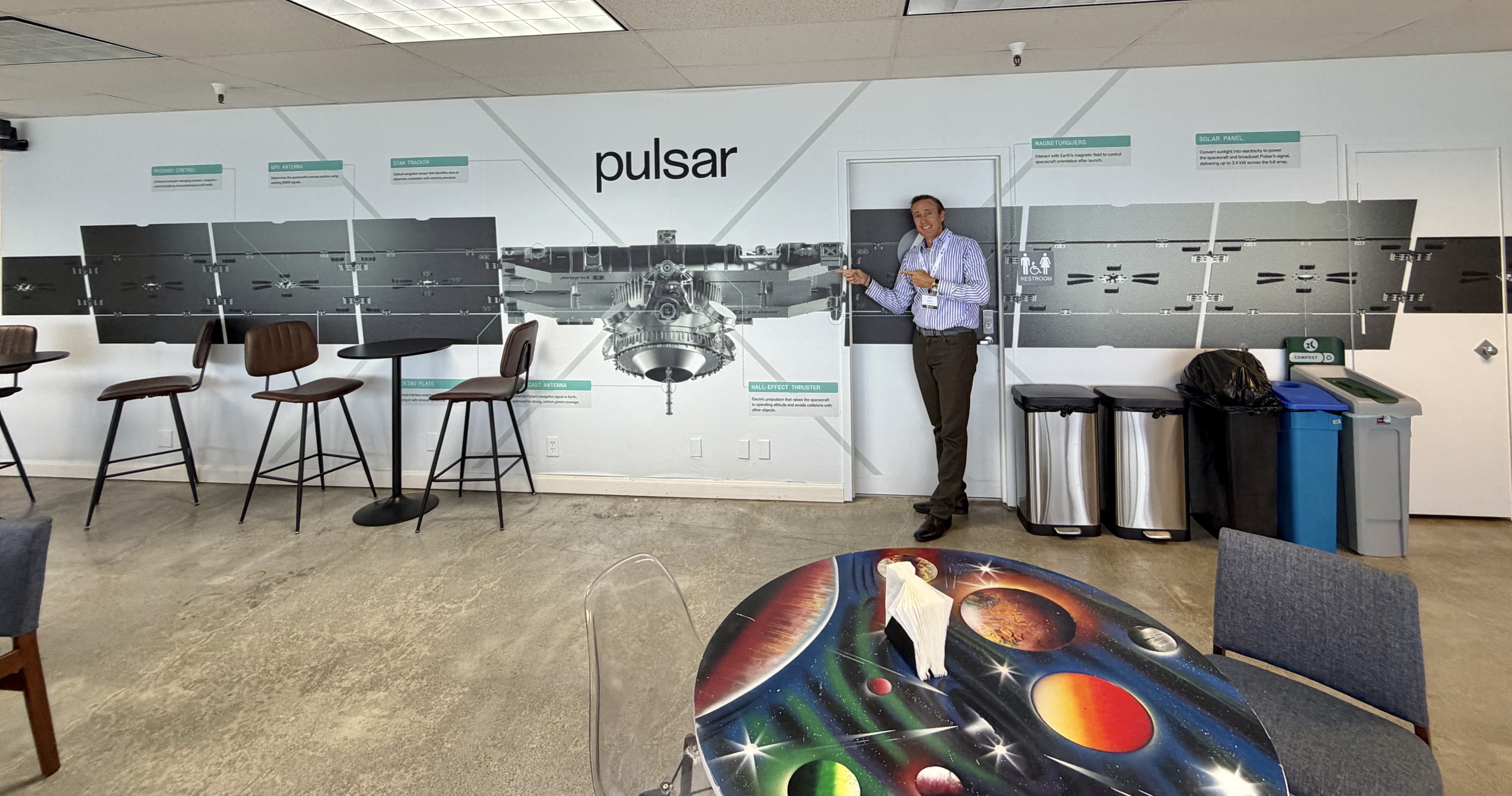 A full-scale wall graphic of a Xona Pulsar navigation satellite with its solar wings unfolded, at the company's headquarters in August 2026.